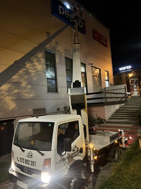 Podnośnik koszowy RADMAT montuje szyld Pepco nocą